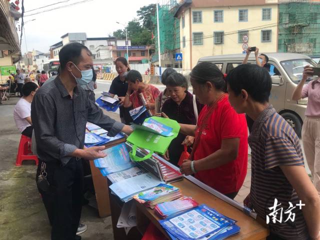 九陂鎮(zhèn)人大主席黃成志（左一）給群眾派發(fā)法治宣傳單和環(huán)保袋。
